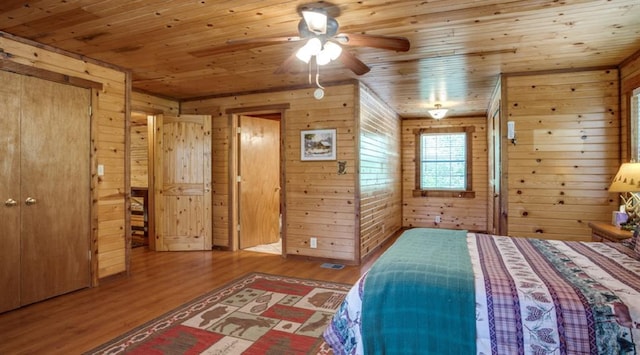 unfurnished bedroom featuring wooden walls, hardwood / wood-style floors, ceiling fan, and wood ceiling