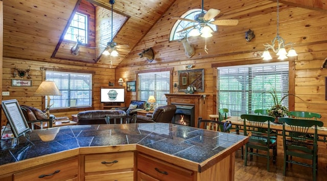 kitchen with hardwood / wood-style floors, plenty of natural light, ceiling fan with notable chandelier, and wooden walls