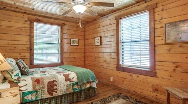 bedroom with hardwood / wood-style flooring, ceiling fan, wood ceiling, and wooden walls