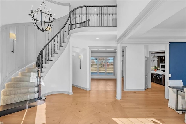 entryway with parquet floors, sink, an inviting chandelier, and ornamental molding