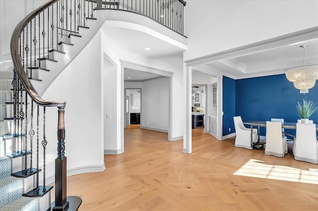 entrance foyer featuring a notable chandelier, parquet flooring, and crown molding