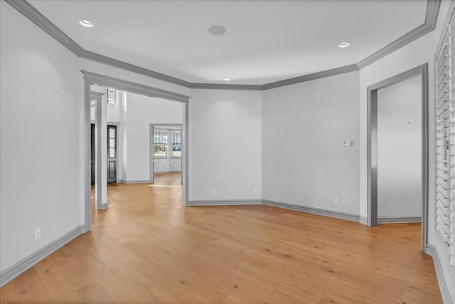 empty room featuring light wood-type flooring and crown molding