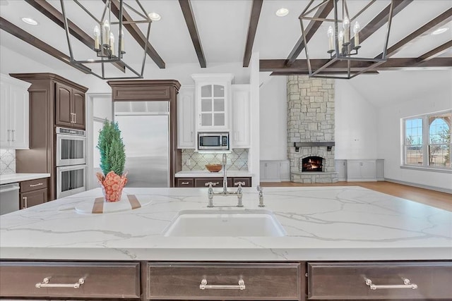 kitchen featuring built in appliances, hardwood / wood-style flooring, dark brown cabinetry, a fireplace, and white cabinetry