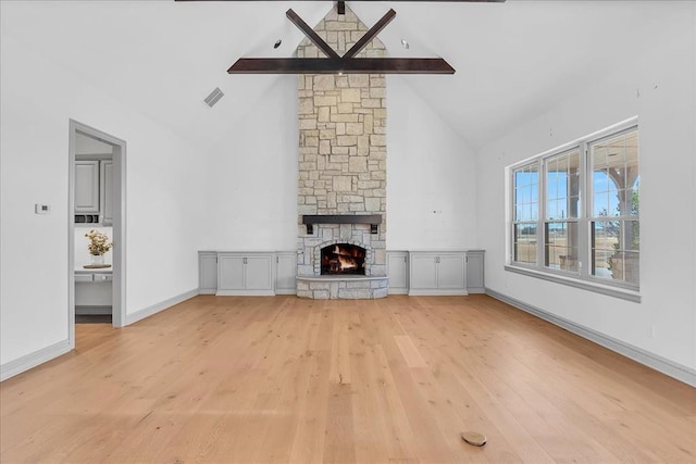 unfurnished living room featuring a fireplace, beam ceiling, high vaulted ceiling, and light hardwood / wood-style flooring