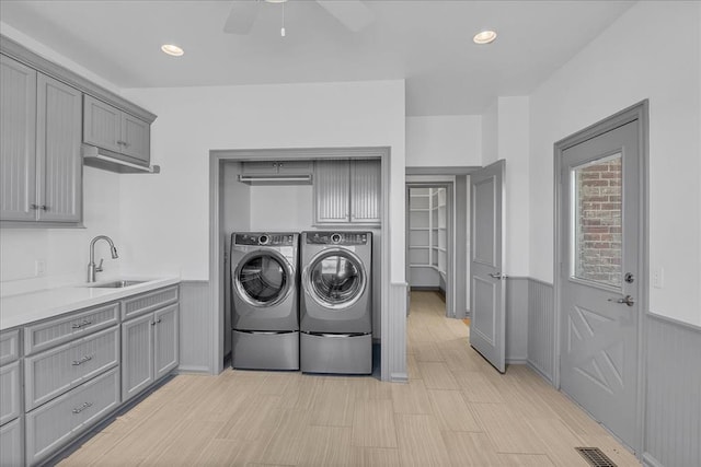 laundry area with independent washer and dryer, light wood-type flooring, ceiling fan, and sink