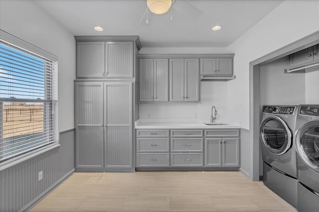 laundry area with ceiling fan, sink, cabinets, separate washer and dryer, and light wood-type flooring