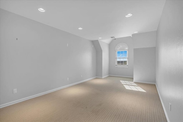 carpeted spare room with vaulted ceiling