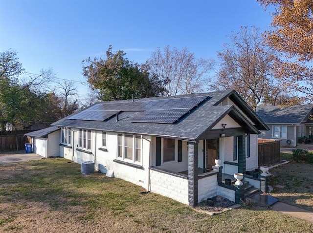 view of front of house featuring a front yard, solar panels, an outdoor structure, and covered porch