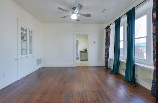 spare room with a textured ceiling, dark hardwood / wood-style floors, ceiling fan, and a healthy amount of sunlight