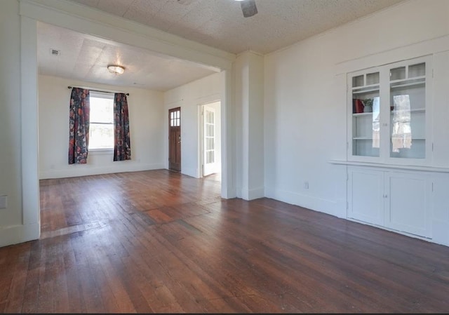 empty room with a textured ceiling, dark hardwood / wood-style floors, and ceiling fan