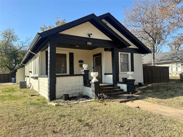 bungalow with cooling unit, a porch, and a front lawn