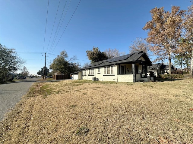 view of home's exterior with solar panels, central air condition unit, and a lawn