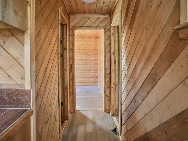 hall featuring light hardwood / wood-style floors and wooden walls