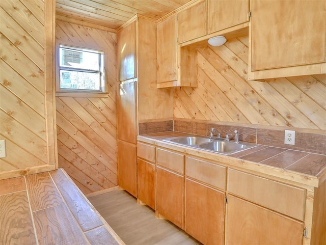 kitchen with wooden ceiling, sink, wooden walls, light hardwood / wood-style flooring, and tile counters