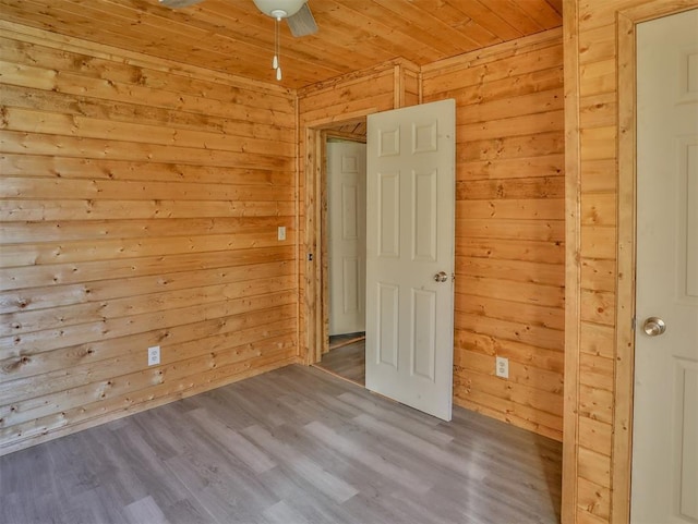 spare room with wooden walls, hardwood / wood-style floors, ceiling fan, and wood ceiling