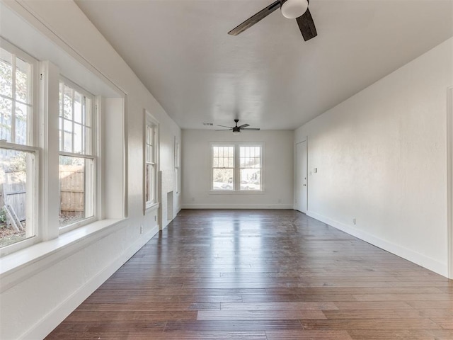 empty room featuring ceiling fan, plenty of natural light, and dark wood-type flooring