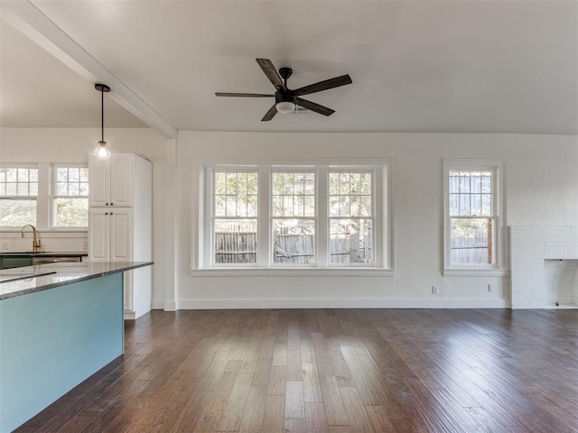 unfurnished living room featuring plenty of natural light, dark wood-type flooring, and ceiling fan