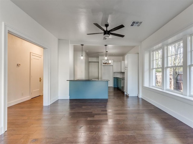 unfurnished living room featuring ceiling fan with notable chandelier and dark hardwood / wood-style floors