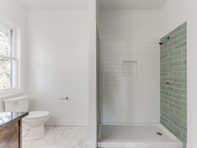 bathroom with a tile shower, tile patterned floors, vanity, and toilet