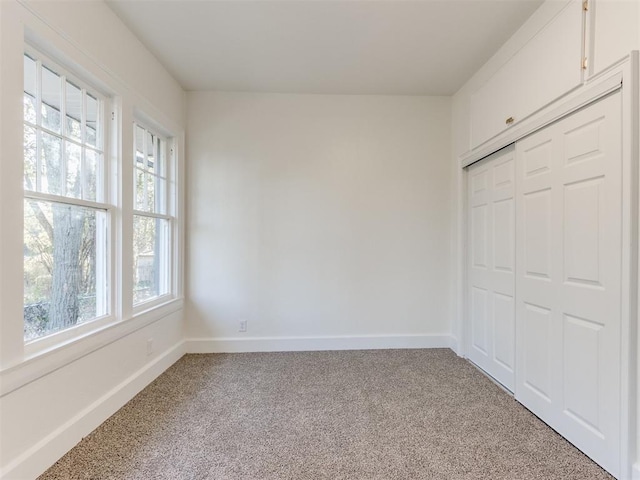 unfurnished bedroom with carpet, a closet, and multiple windows