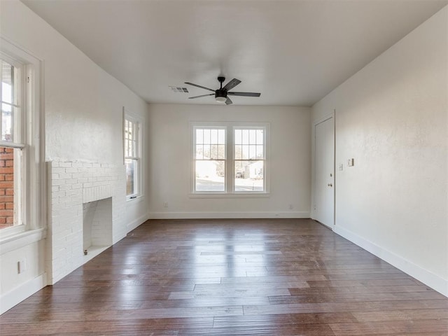 unfurnished living room featuring a brick fireplace, ceiling fan, and dark wood-type flooring