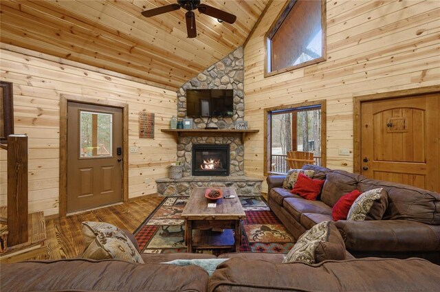 living room featuring a fireplace, light hardwood / wood-style floors, a healthy amount of sunlight, and wood walls