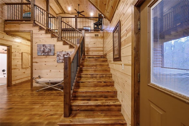 stairway featuring wooden walls, ceiling fan, vaulted ceiling, and hardwood / wood-style flooring