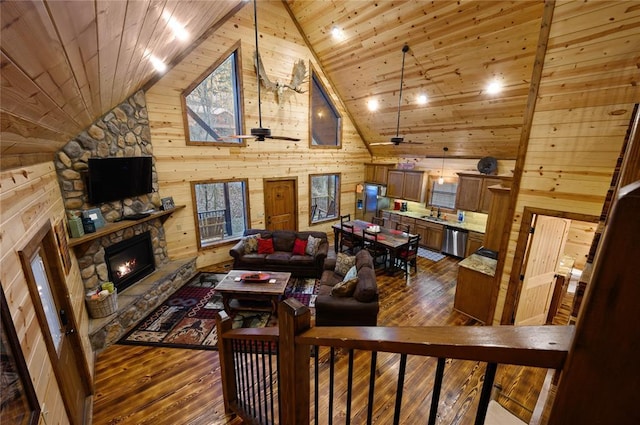 living room with ceiling fan, hardwood / wood-style floors, wooden walls, a fireplace, and wood ceiling