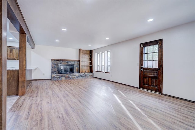 unfurnished living room featuring a fireplace, a healthy amount of sunlight, and light wood-type flooring