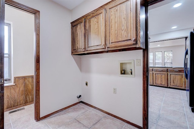 washroom with hookup for an electric dryer, cabinets, light tile patterned floors, and washer hookup