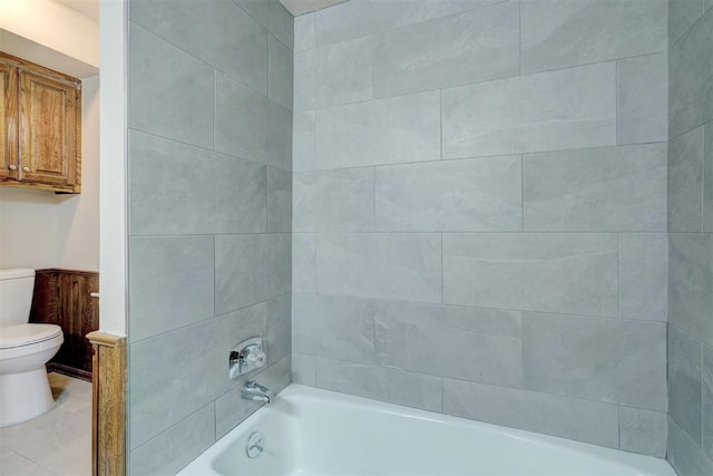 bathroom featuring tile patterned flooring, tiled shower / bath combo, and toilet