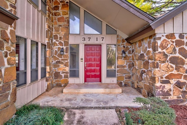 view of exterior entry with board and batten siding and stone siding