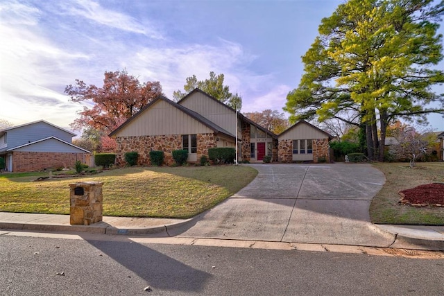 mid-century home featuring stone siding, driveway, and a front lawn