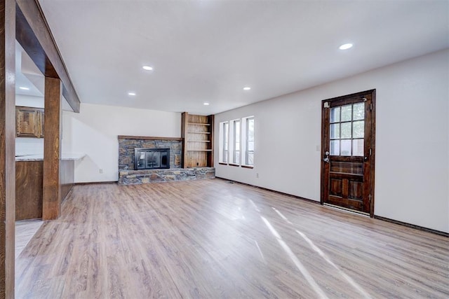 unfurnished living room featuring light wood-type flooring, a stone fireplace, baseboards, and recessed lighting