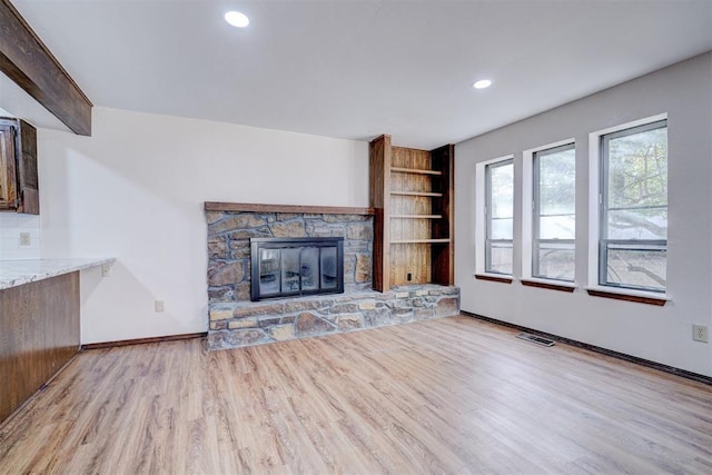 unfurnished living room featuring a stone fireplace, recessed lighting, visible vents, baseboards, and light wood-type flooring