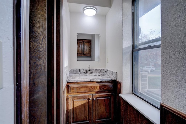 bathroom featuring a textured wall and vanity