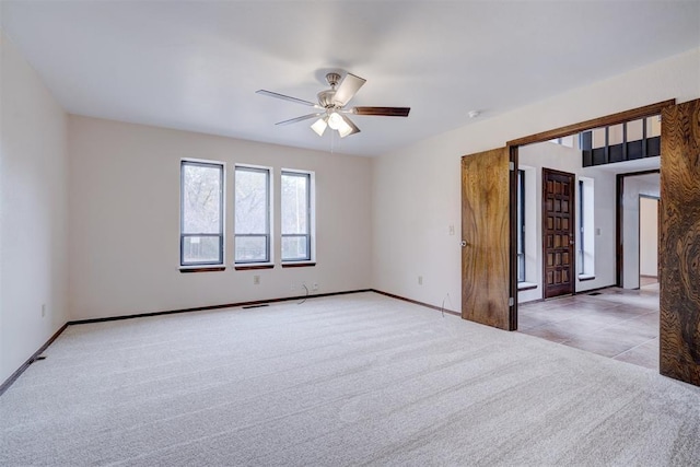 spare room with carpet floors, a ceiling fan, and baseboards