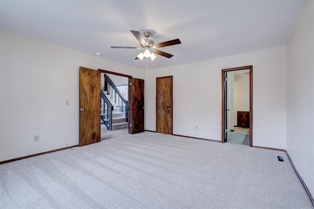 unfurnished bedroom with connected bathroom, light colored carpet, ceiling fan, and baseboards