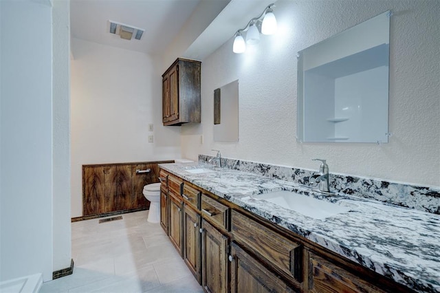 full bath with visible vents, double vanity, a sink, and toilet