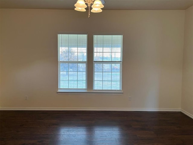 unfurnished room featuring a chandelier and dark hardwood / wood-style floors