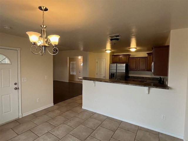 kitchen featuring pendant lighting, appliances with stainless steel finishes, a notable chandelier, kitchen peninsula, and a breakfast bar area