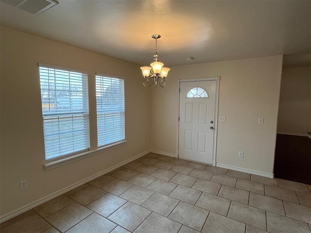 entrance foyer featuring a healthy amount of sunlight, light tile patterned floors, and a chandelier