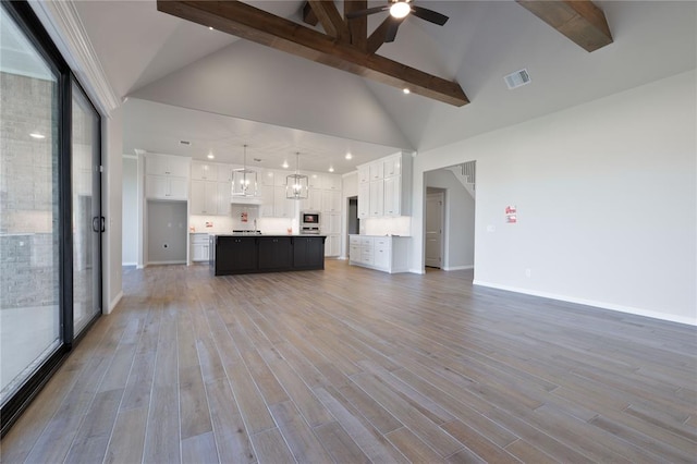 unfurnished living room featuring beam ceiling, high vaulted ceiling, light hardwood / wood-style flooring, and ceiling fan