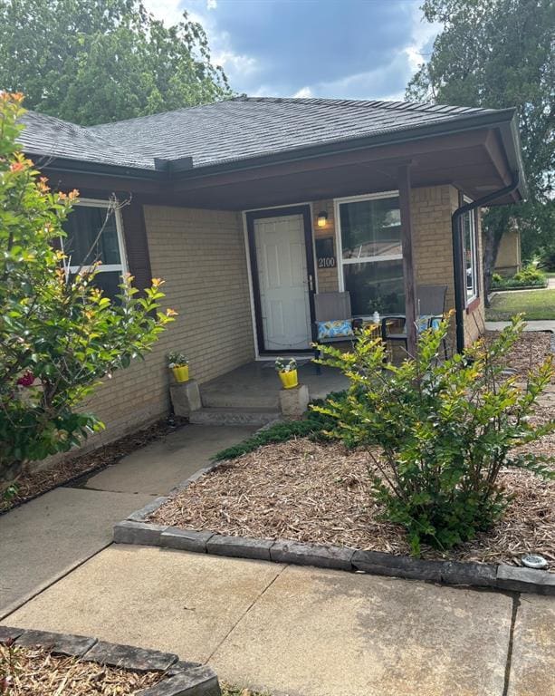 2100 Barclay Rd, Oklahoma City, OK 73120 - view of exterior entry featuring brick siding, a porch, and roof with shingles