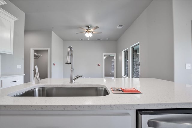 kitchen featuring ceiling fan, light stone counters, white cabinetry, and sink