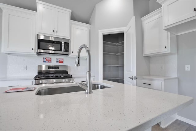 kitchen with tasteful backsplash, white cabinetry, sink, and stainless steel appliances