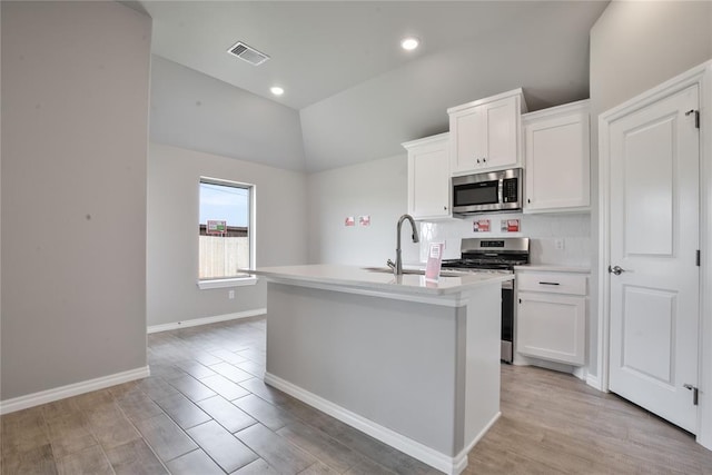 kitchen featuring lofted ceiling, an island with sink, light hardwood / wood-style floors, white cabinetry, and stainless steel appliances