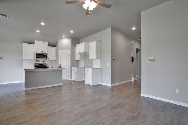 kitchen with a kitchen island with sink, sink, appliances with stainless steel finishes, white cabinetry, and wood-type flooring