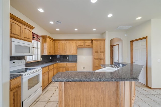 kitchen featuring a center island with sink, light tile patterned floors, white appliances, and sink