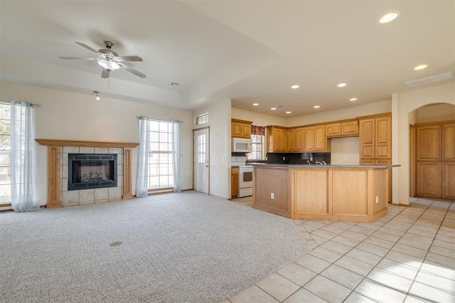 kitchen featuring ceiling fan, a healthy amount of sunlight, light colored carpet, and white appliances